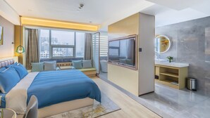 A modern hotel room with a large bed, a TV, a bathroom with a mirror, and a city view. - Lidu International Hotel (Handan)