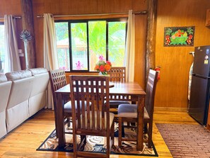 A dining area with a wooden table, chairs, and a vase of flowers.