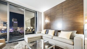 A modern living room with a sofa, a glass coffee table, and a view of a cityscape through a sliding glass door. - SVS: Strip View Studio | Open Balcony | Pool Access | Palms Place (Las Vegas)