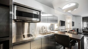 A modern kitchen with stainless steel appliances, a built-in oven, and a dining area with a table and chairs. - SVS: Strip View Studio | Open Balcony | Pool Access | Palms Place (Las Vegas)
