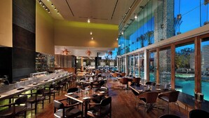 Ein geräumiges Restaurant mit einer langen Theke, mehreren Tischen und Blick auf einen Swimmingpool.