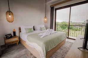 A bedroom with a large bed, a nightstand, a TV, and a balcony with a view.
