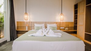 Habitación de hotel con una cama grande, dos mesitas de noche, un armario de madera y una ventana con cortinas.