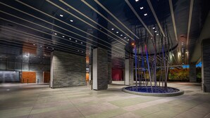 Eine großzügige Lobby mit modernem Design, inklusive einer zentralen Skulptur und einem Fliesenboden.