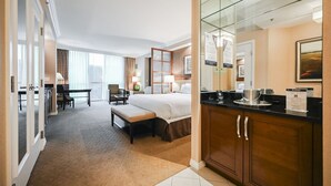 Ein Hotelzimmer mit einem großen Bett, einem Schreibtisch, einem Stuhl, einem kleinen Tisch, einer Couch und einer Kaffeemaschine sowie einem Spiegel.