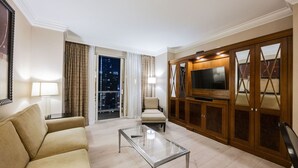 A hotel room with a sofa, a glass coffee table, a TV on a wooden cabinet, and a view of the city at night. - SVS: 2BD Suite | SPHERE Strip Views | Private Balcony | Signature at MGM (Las Vegas)