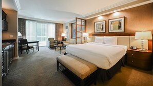 A hotel room with a large bed, a desk, a chair, a bench, a TV, and a window with curtains. - SVS: Strip View Studio | Private Balcony | Pool & Gym | Signature at MGM (Las Vegas)