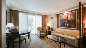 A hotel room with a dining table, two chairs, a sofa, a coffee table, and a painting on the wall. - SVS: Strip View Studio | Private Balcony | Pool & Gym | Signature at MGM (Las Vegas)