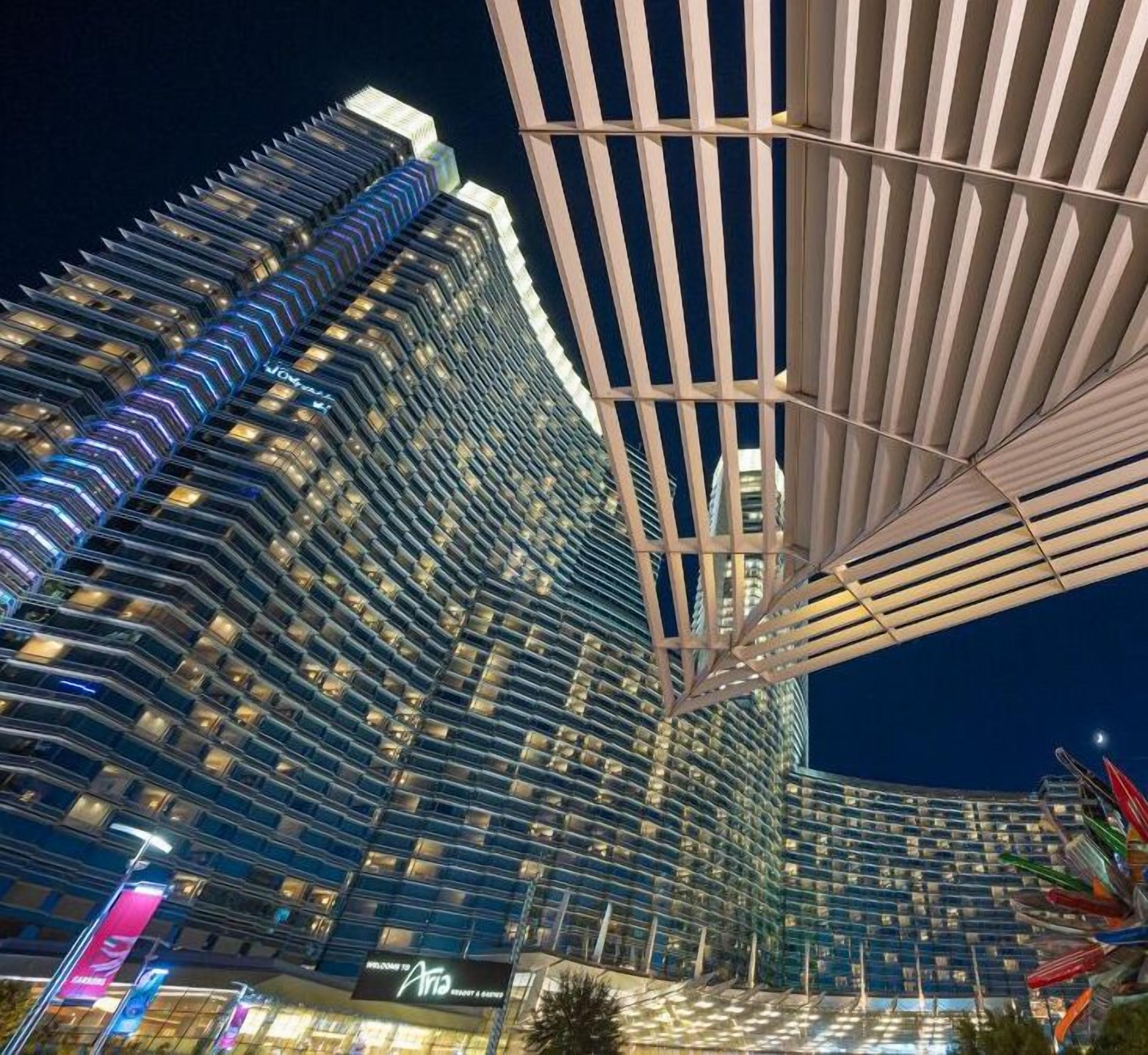 A high-rise hotel with a modern design, featuring a distinctive sloped facade and a large, open-air structure with a grid-like pattern.