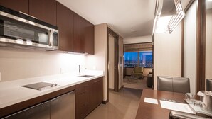 Uma cozinha moderna com eletrodomésticos de aço inoxidável, uma sala de jantar com mesa e cadeiras, e vista para a cidade à noite.