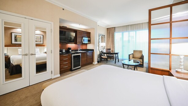 Een hotelkamer met een groot bed, een kitchenette, een eethoek en uitzicht op de omgeving.