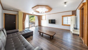 Ein geräumiges Wohnzimmer mit einer großen Couch, einem Couchtisch und einem flachbildfernseher an der Wand.