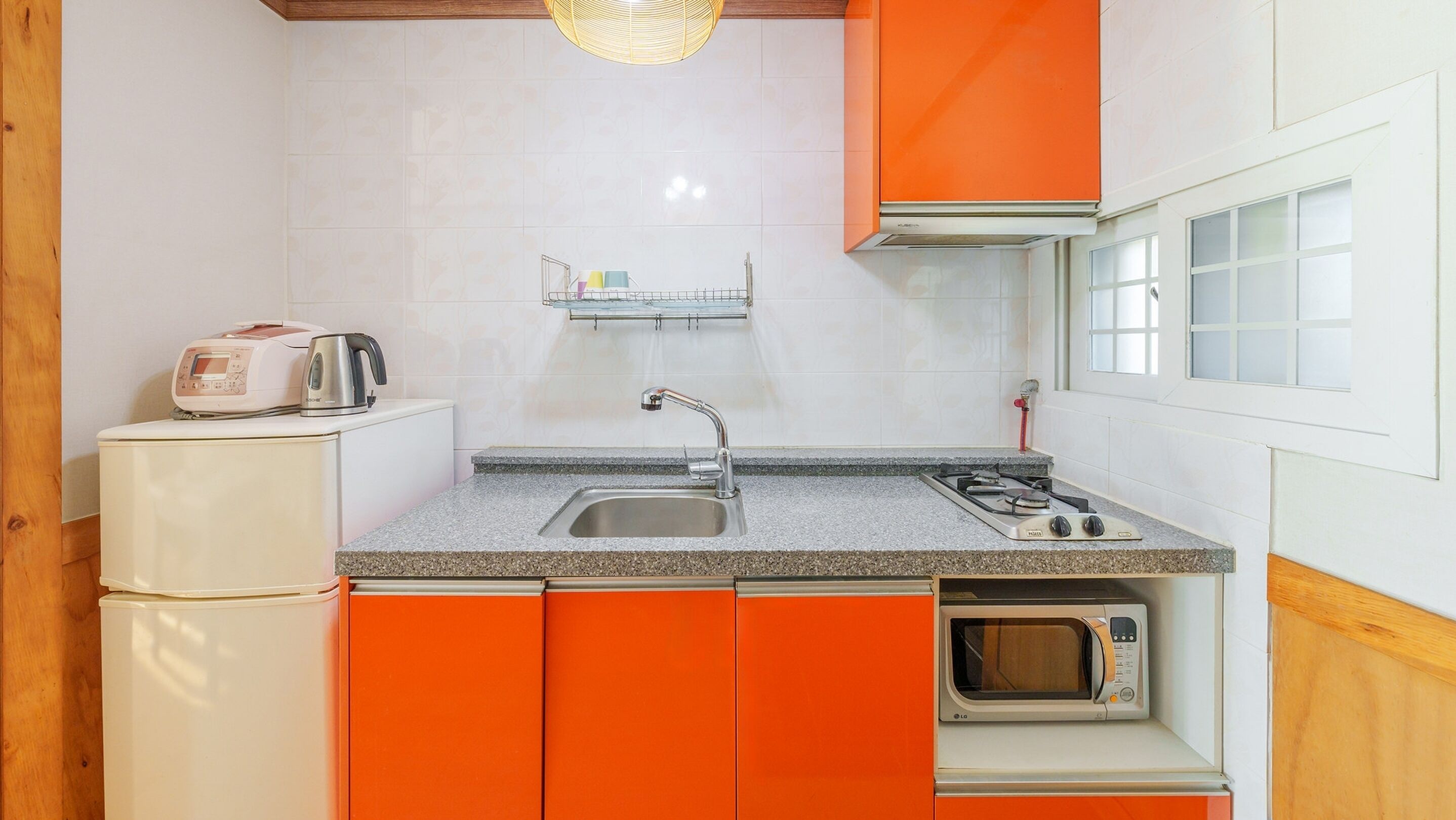 Una cocina compacta con fregadero, estufa y microondas.