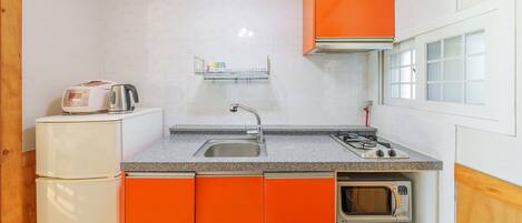 Una cocina compacta con fregadero, estufa y microondas.