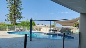 Una piscina con lettini e una zona ombreggiata.