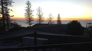 Vista di un balcone con un tramonto, alberi e un corpo d'acqua.