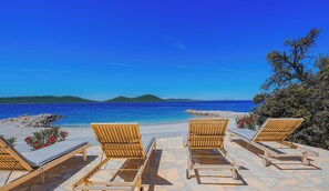A beachside lounge with wooden loungers and a view of the sea.