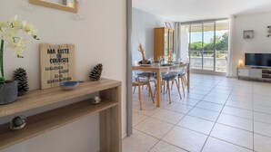 A dining area with a wooden table and chairs, a television, and a view of the outdoors. - Arcachon Marines by Interhome (Arcachon)