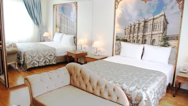 Habitación de hotel con dos camas, un sofá y un espejo grande.
