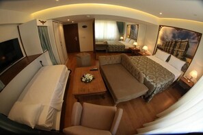 A hotel room with a bed, two sofas, a small table, a TV, and a painting on the wall. - Elite Marmara Ortaköy Hotel & Suites (Istanbul)