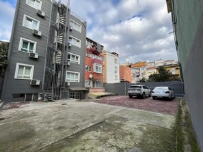 A multi-story residential building with a fire escape, a parking area with two cars, and a red brick pathway. - Elite Marmara Ortaköy Hotel & Suites (Istanbul)