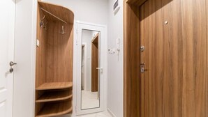 A hallway with a wooden wardrobe, a mirror, and a white door.