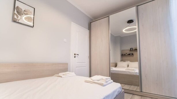 A modern bedroom with a bed, a wardrobe, and a mirror.