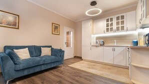 A modern kitchen with white cabinets and a blue sofa in a living area.