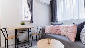 A modern living room with a grey sofa, two black chairs, a wooden table, and a small potted plant. - City Center Studio Apartments 1 (Plovdiv)