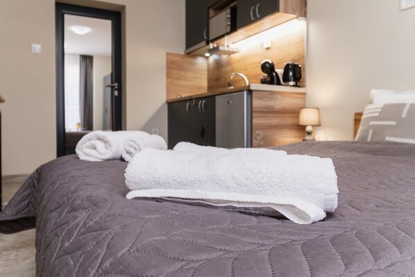 Cozy retreat with a neatly made bed, vanity, and coffee maker.