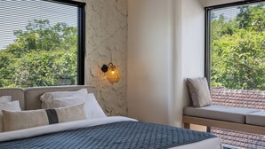 Un dormitorio con cama, sofá y lámpara fijada a la pared.