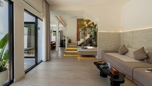 Una sala de estar moderna con sofá, mesa de centro y una escalera que lleva a un comedor.