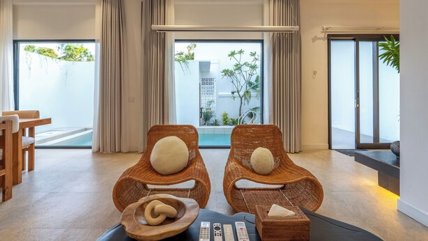 Una habitación moderna con dos sillas de mimbre, una mesa de madera y vistas a zonas verdes.
