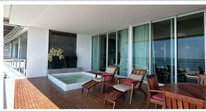 Relax on the outdoor deck with a hot tub, lounge chairs, and dining table, offering breathtaking ocean views.