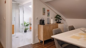 Une chambre moderne avec un bureau en bois, une chaise, une plante en pot et un petit meuble.