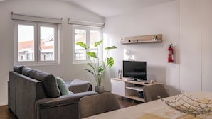 Un salon moderne avec un canapé, un téléviseur, une table à manger et une plante en pot.