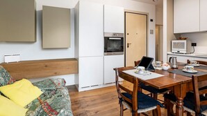 A modern kitchen with white cabinets, a built-in oven, and a microwave. There is a dining table with chairs and a laptop. - GuestHost - Rimini Oasis of Peace & Relaxation! (Rimini)