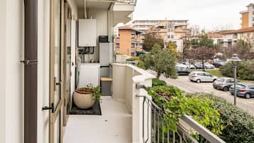 Un balcone con vista su auto parcheggiate e palazzi.