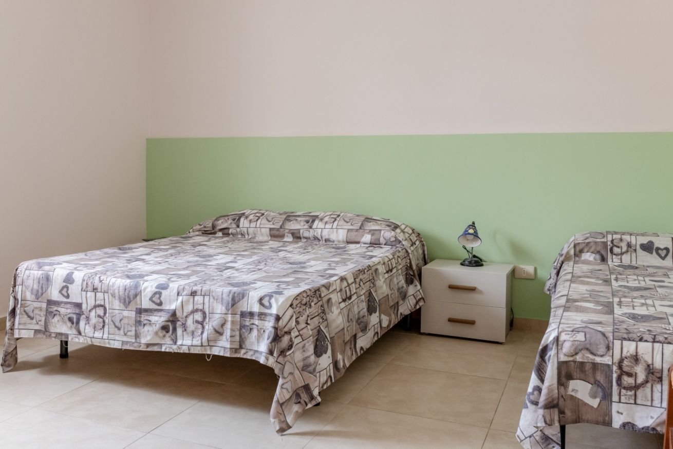 Une chambre avec deux lits, une table de chevet et une lampe.