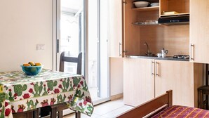 Una cocina compacta con una mesa de comedor, un tazón azul y un mantel estampado con motivos de cactus.