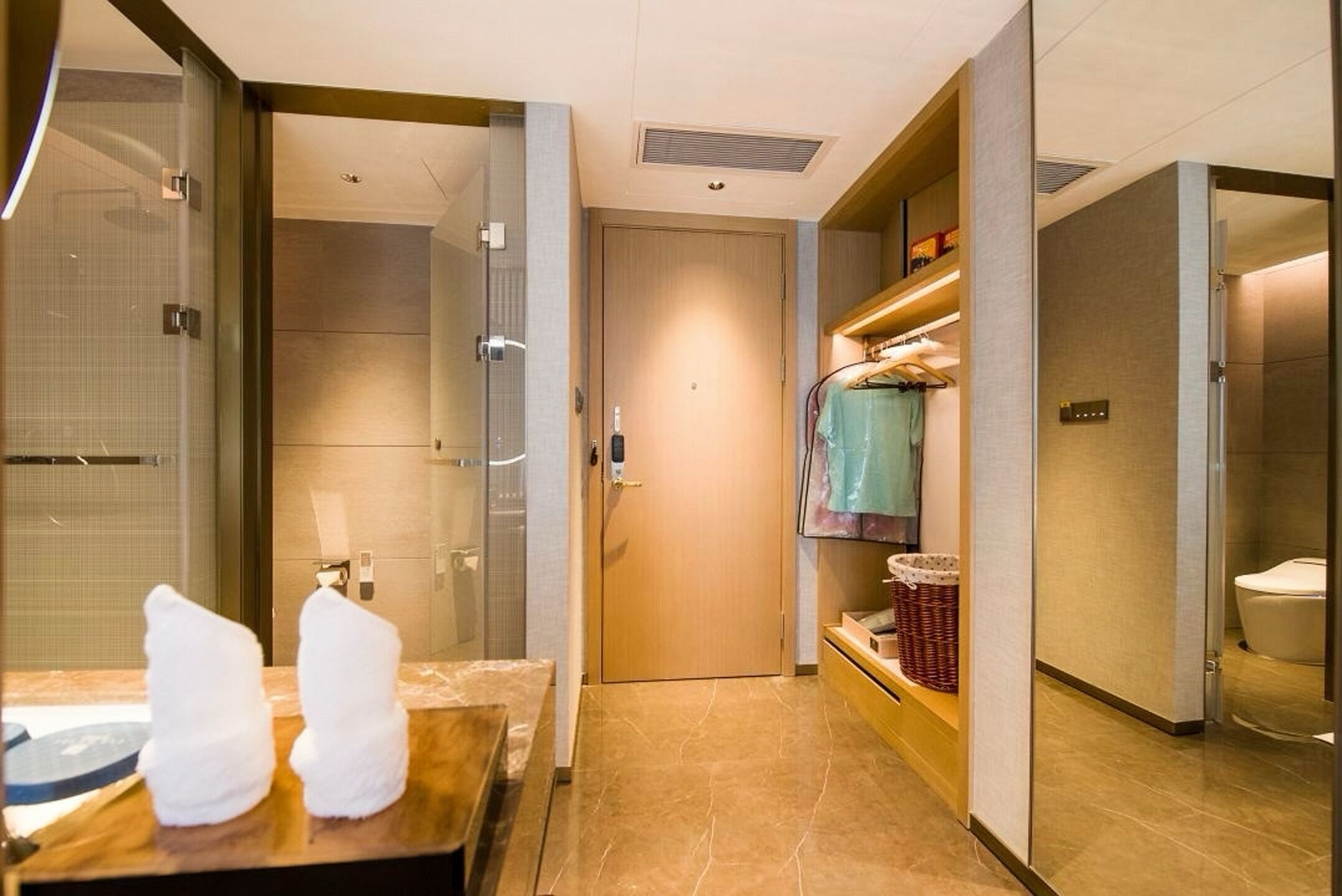 A hotel bathroom with a shower, toilet, and a vanity with towels.