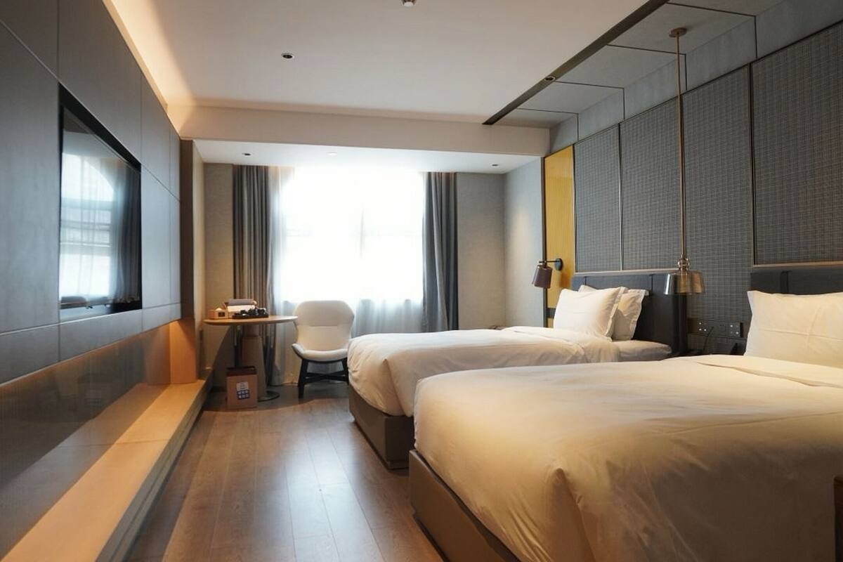 Une chambre d’hôtel avec deux lits, un bureau et une chaise.