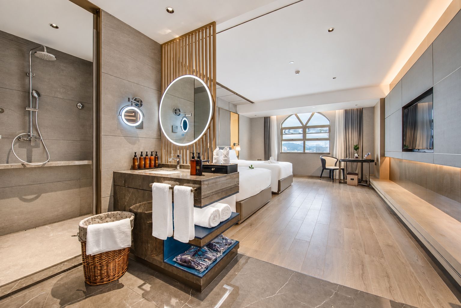 A modern hotel bathroom with a shower, a vanity with a mirror, and a seating area with a table and chairs.