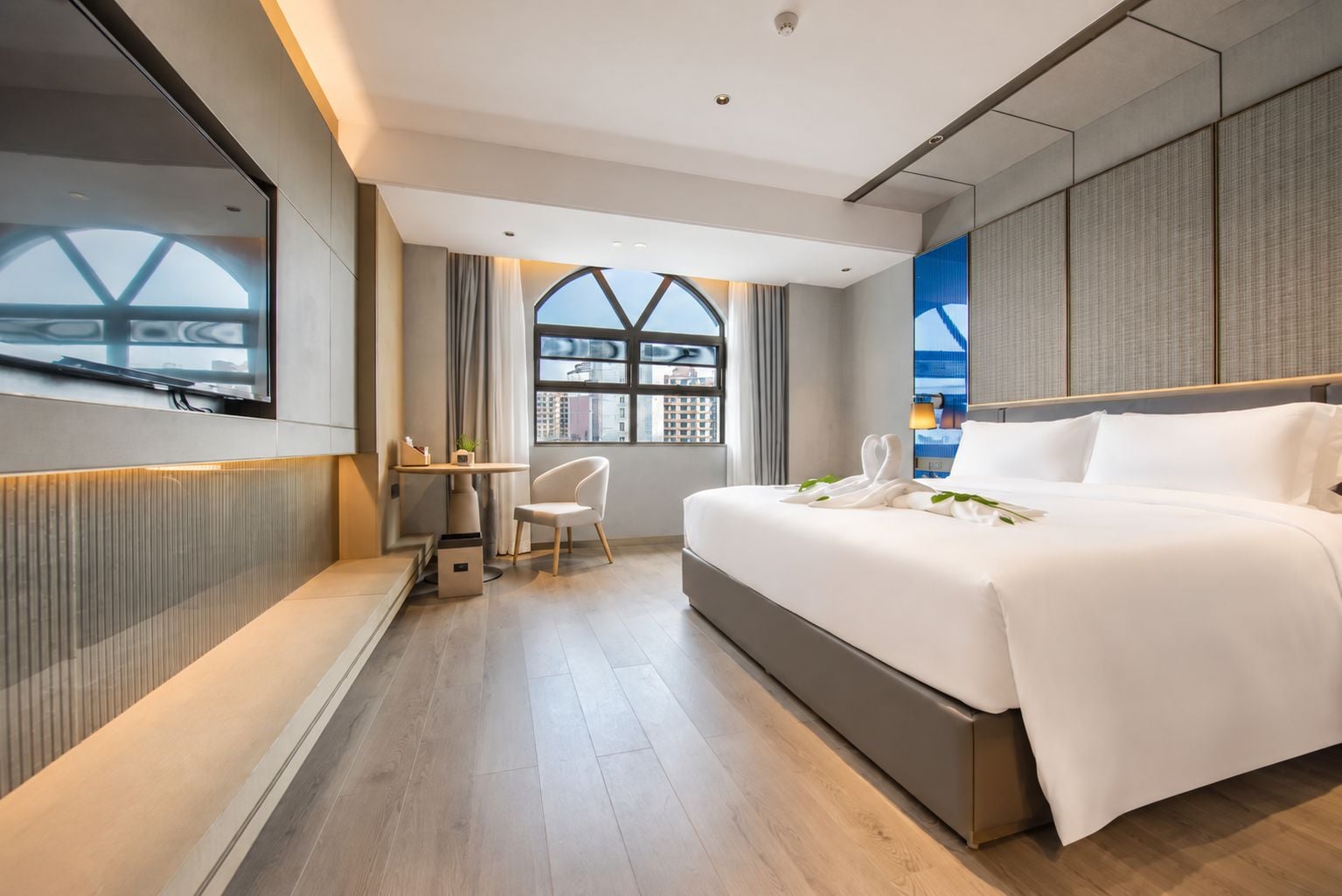 Een moderne hotelkamer met een groot bed, een bureau en uitzicht door een raam.