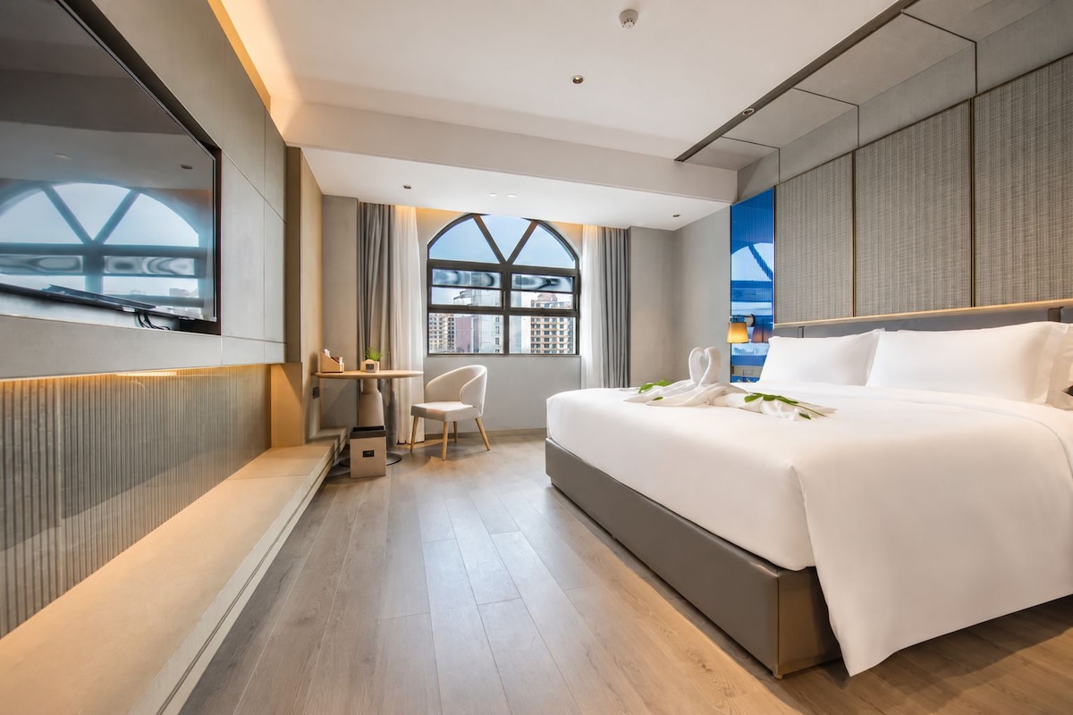 Et moderne hotelværelse med en stor seng, et skrivebord og udsigt fra et vindue.
