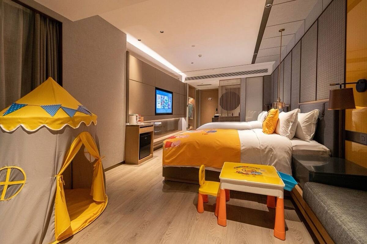 Une chambre d’hôtel comprenant un lit, un petit bureau, une télévision, une tente de jeu et une petite table avec une chaise.