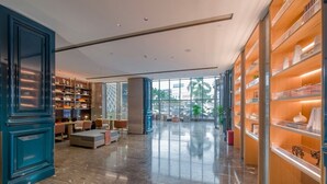 A spacious lobby with a marble floor, a seating area with sofas, and a large window offering a view of the outside.