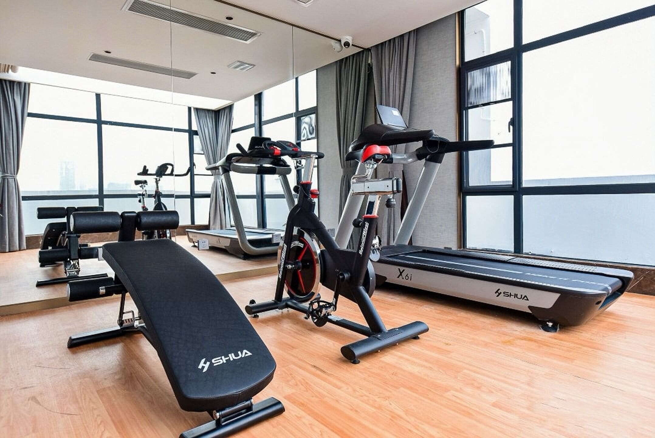 A gym with exercise equipment including a treadmill, stationary bikes, and a bench.