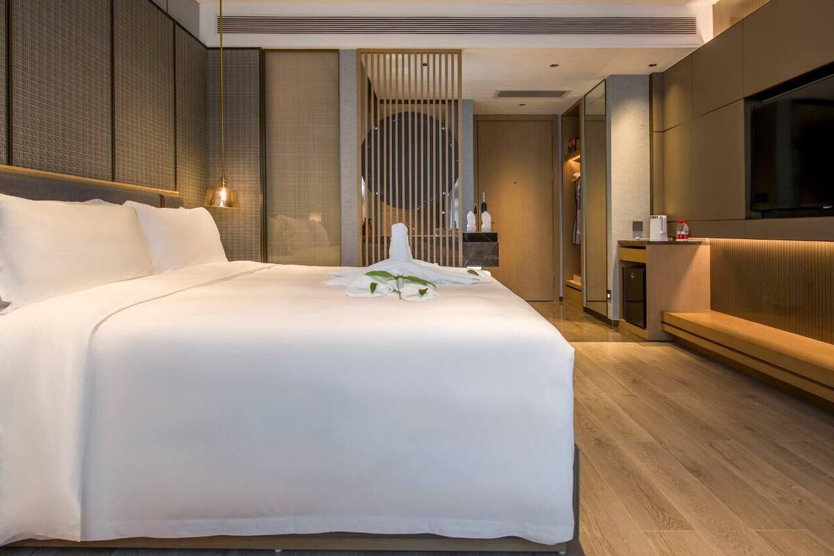Une chambre d’hôtel moderne avec un grand lit, un canapé, une télévision et un miroir.