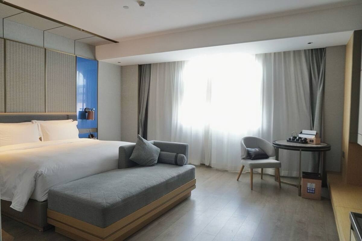 Une chambre d’hôtel moderne avec un grand lit, un canapé, un fauteuil et une petite table.